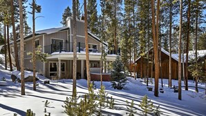 A two-story lodge with a balcony, surrounded by snow-covered ground and tall pine trees. - Hot Tub! Family Gem on Snake River in Keystone! (Keystone)