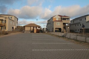 A parking lot with paved ground, a building with a brown roof, and a staircase leading to a second floor.