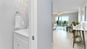 Ein modernes Badezimmer mit Waschtisch, Handtuchhalter und Blick auf einen Balkon mit Sitzgelegenheit.