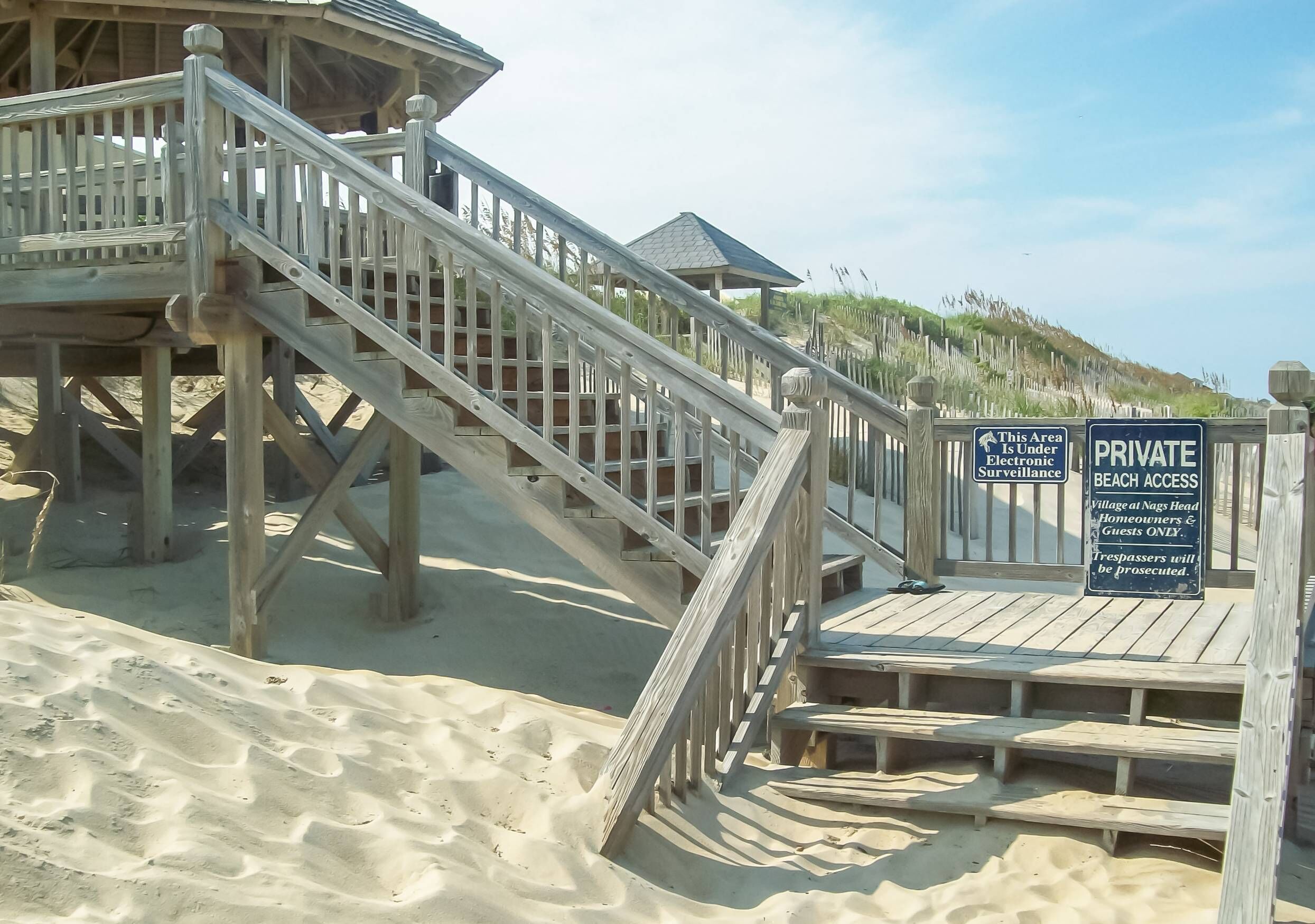 Eine Holztreppe führt zu einer privaten Strandbucht, mit einem Schild, das Zugangsbeschränkungen anzeigt.