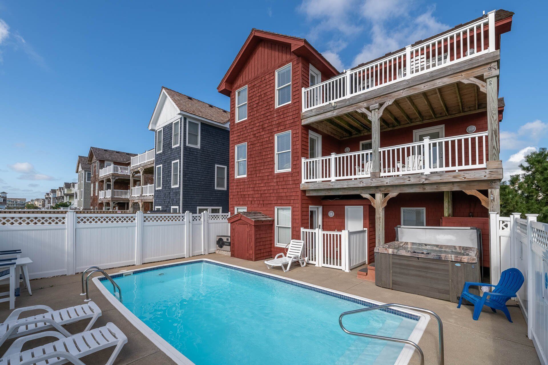 Un quartier résidentiel doté d’une piscine, de chaises longues blanches et d’un jacuzzi.