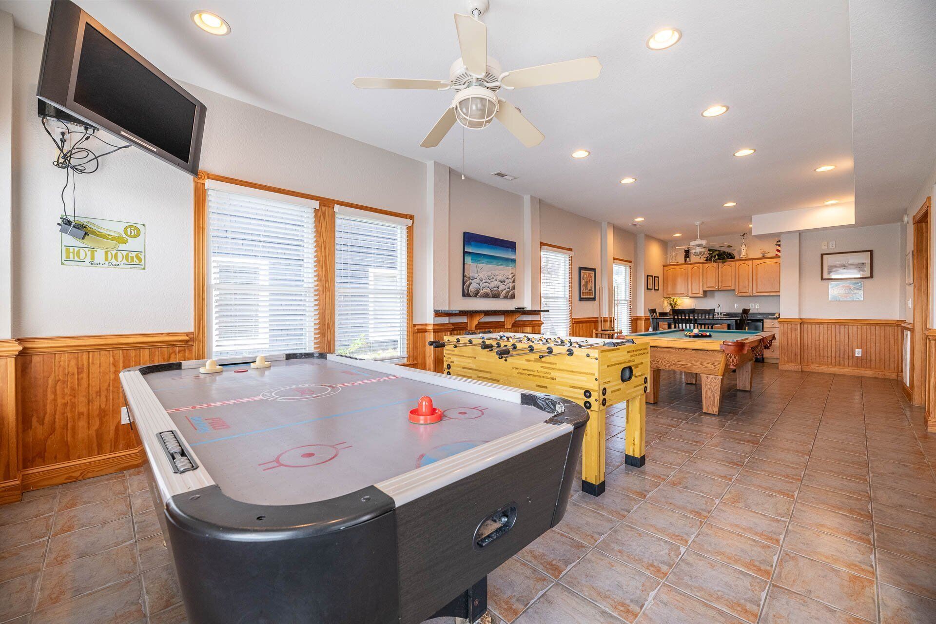 A spacious recreational room with a foosball table, a pool table, and a ceiling fan.