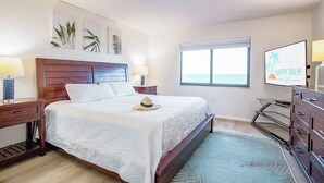 A bedroom with a bed, nightstands, a dresser, a window with a view, and wall art. - Unbeatable Views! Direct Oceanfront 8th Floor Gem w/ Private Balcony! 🏖️ (Cape Canaveral)