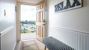 A hallway with a view to the outside, a door, a bench, and a wall with the word 'RELAX' in large letters. - Unbeatable Views! Direct Oceanfront 8th Floor Gem w/ Private Balcony! 🏖️ (Cape Canaveral)