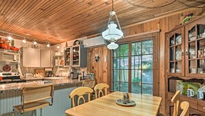 Une cuisine en bois avec une table à manger, des chaises et un luminaire suspendu.
