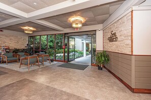 A lobby with a reception desk, seating area, and a large window offering a view of the outdoors. - Cute, cozy 2 bedroom oceanfront condo with free WiFi, a great ocean view, and awesome amenities including indoor/outdoor pools and a game room located uptown! (Ocean City)