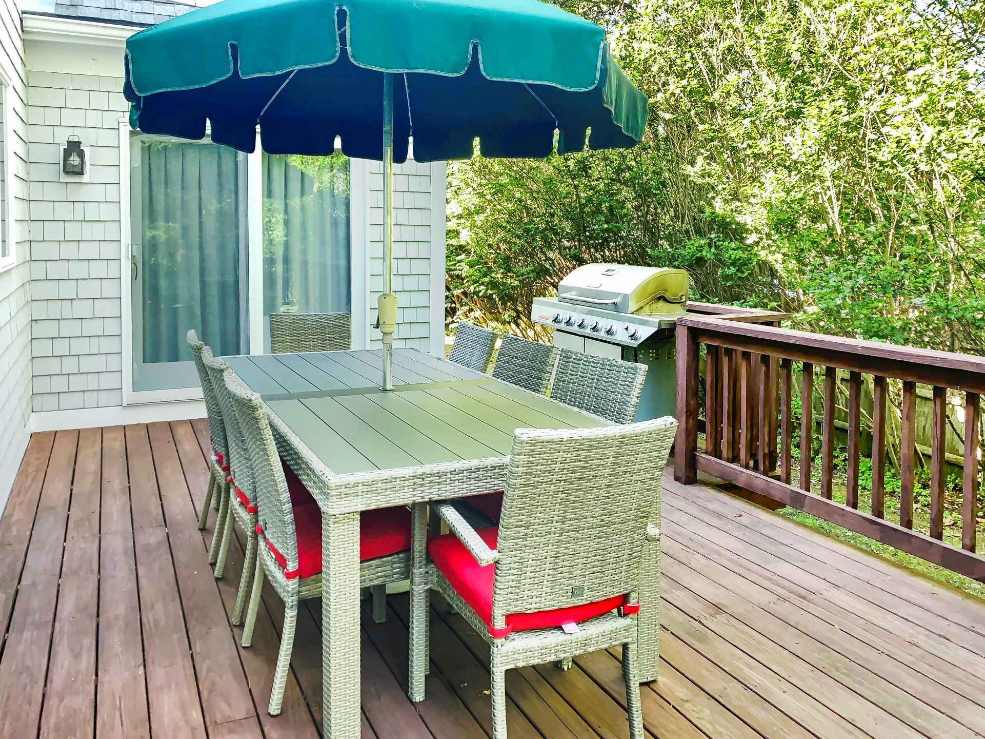 A deck with a table and chairs, a grill, and a covered umbrella.