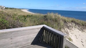 Una terraza de madera con vista a una playa y al océano.