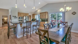 A spacious kitchen with wooden cabinets, a central island, and a dining area with a long table and chairs. - Blackfoot Family Estate (South Lake Tahoe)