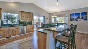 A spacious kitchen with wooden cabinets, a large island, and pendant lighting. - Blackfoot Family Estate (South Lake Tahoe)