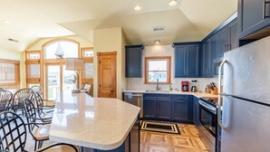 Una cucina con pensili blu scuro, un'isola grande con piano in marmo e un pavimento in legno a herringbone.