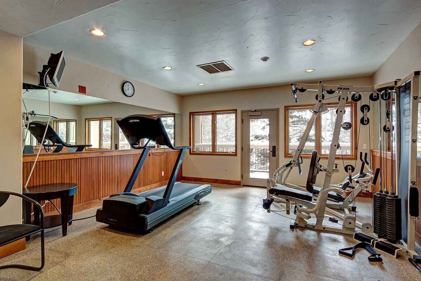 Een sportschool met loopbanden, krachttoestellen en een spiegelwand.