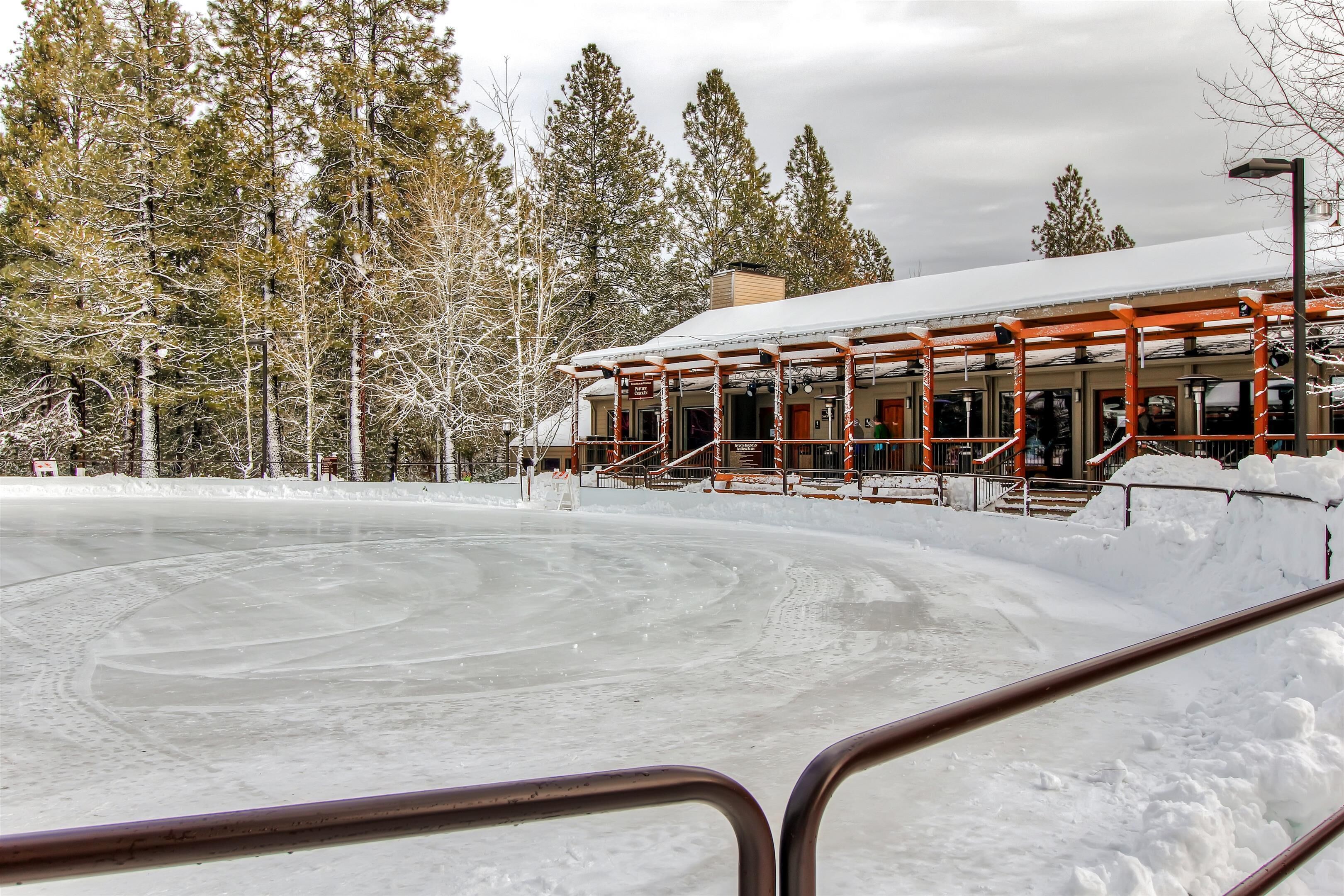 A building with a snow-covered roof, surrounded by trees and a frozen surface.