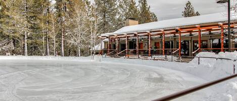 A building with a snow-covered roof, surrounded by trees and a frozen surface.