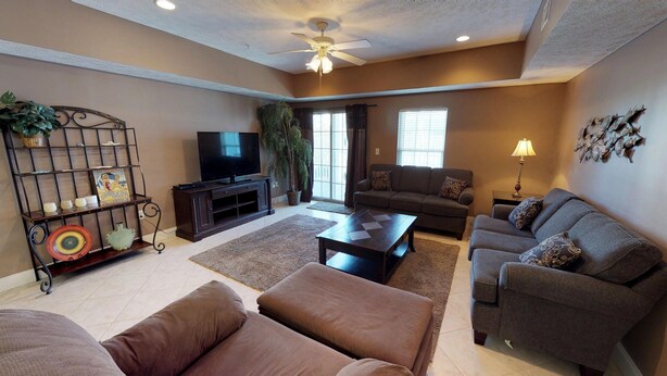 A living room with a television, sofas, a coffee table, and a ceiling fan. - Myrtle Beach Villas 305B - 4 Bedroom Condo (Myrtle Beach)