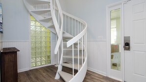 Eine weiße Wendeltreppe in einem Raum mit Holzboden und einer weißen Tür mit Fensterteil.
