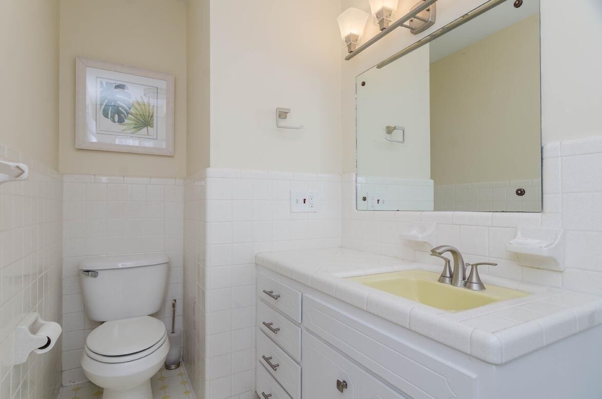 A bathroom with a toilet, sink, and mirror.