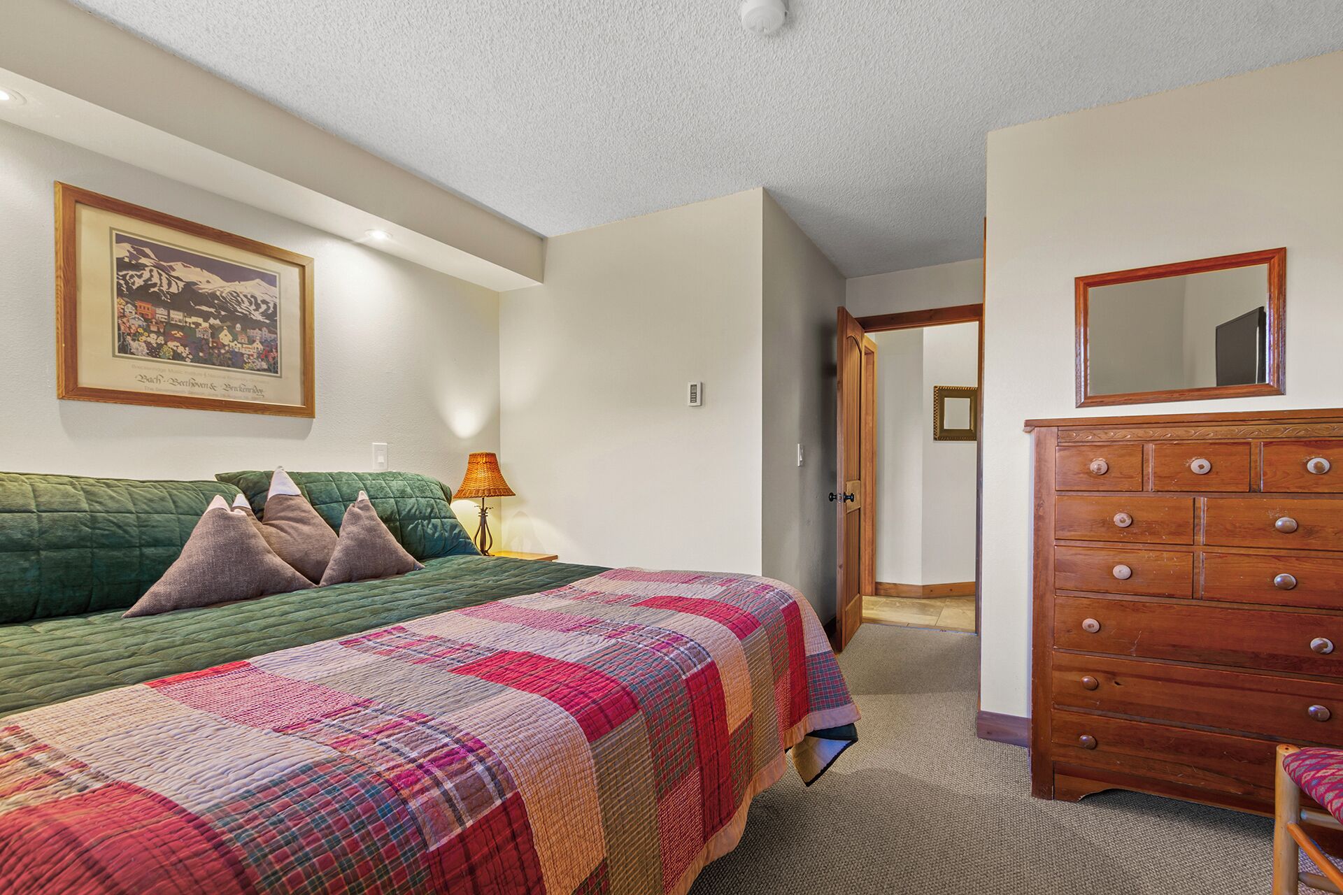 Une chambre à coucher avec un lit, une commode et un tableau encadré au mur.