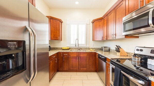 A kitchen with wooden cabinets, a stainless steel refrigerator, a microwave, a stove, and a dishwasher.
