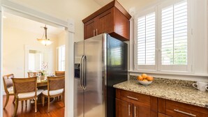 Una cocina con armarios de madera, un refrigerador de acero inoxidable, una encimera de granito y una ventana con persianas.