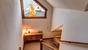 A staircase with a wooden railing, a wooden bench with a lamp, and a stained glass window above. - Ski-In/Ski-Out Luxury Condo - Private Hot Tub! (Breckenridge)