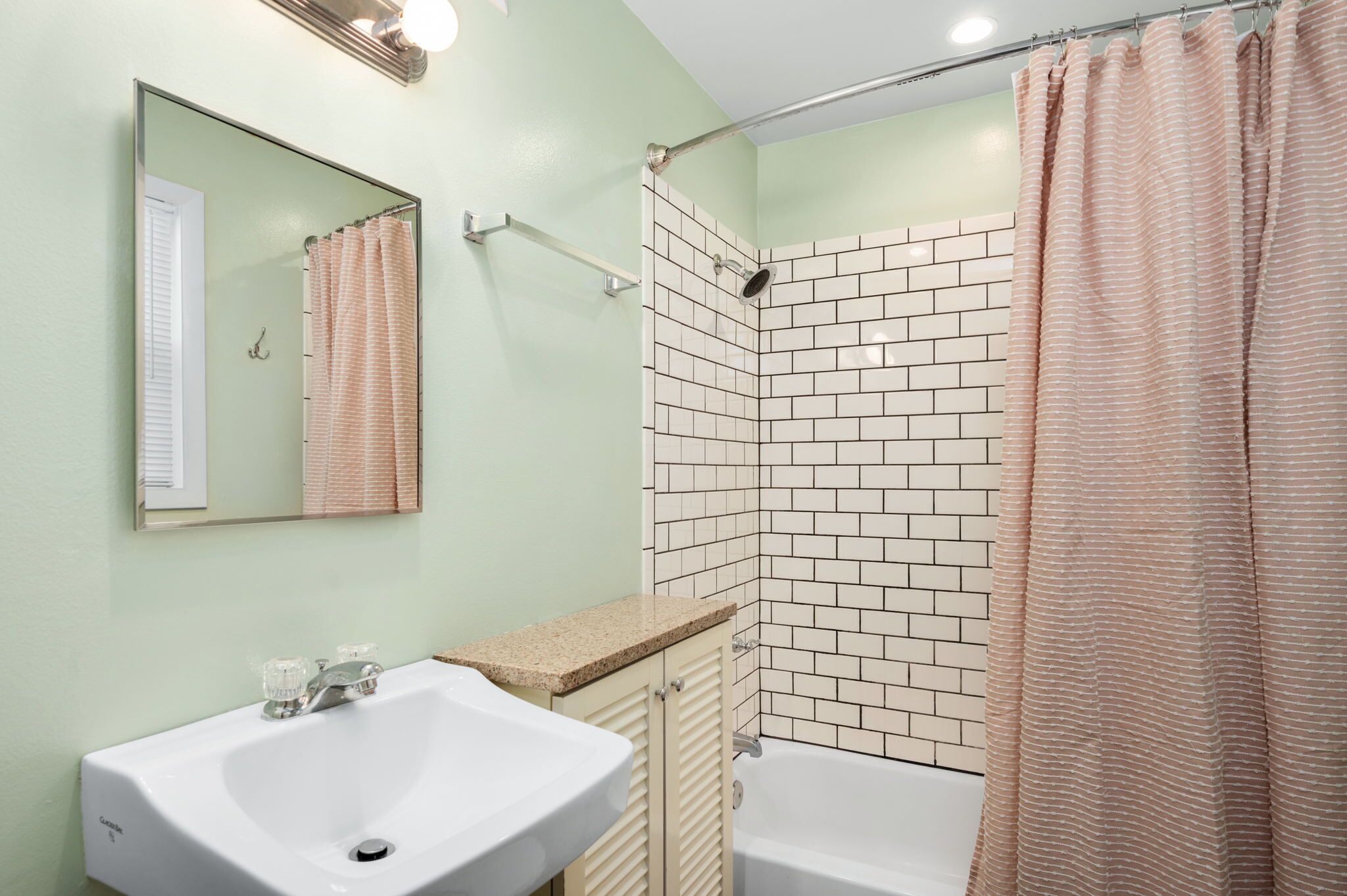Une salle de bain avec un lavabo, un miroir, une douche et des murs carrelés.