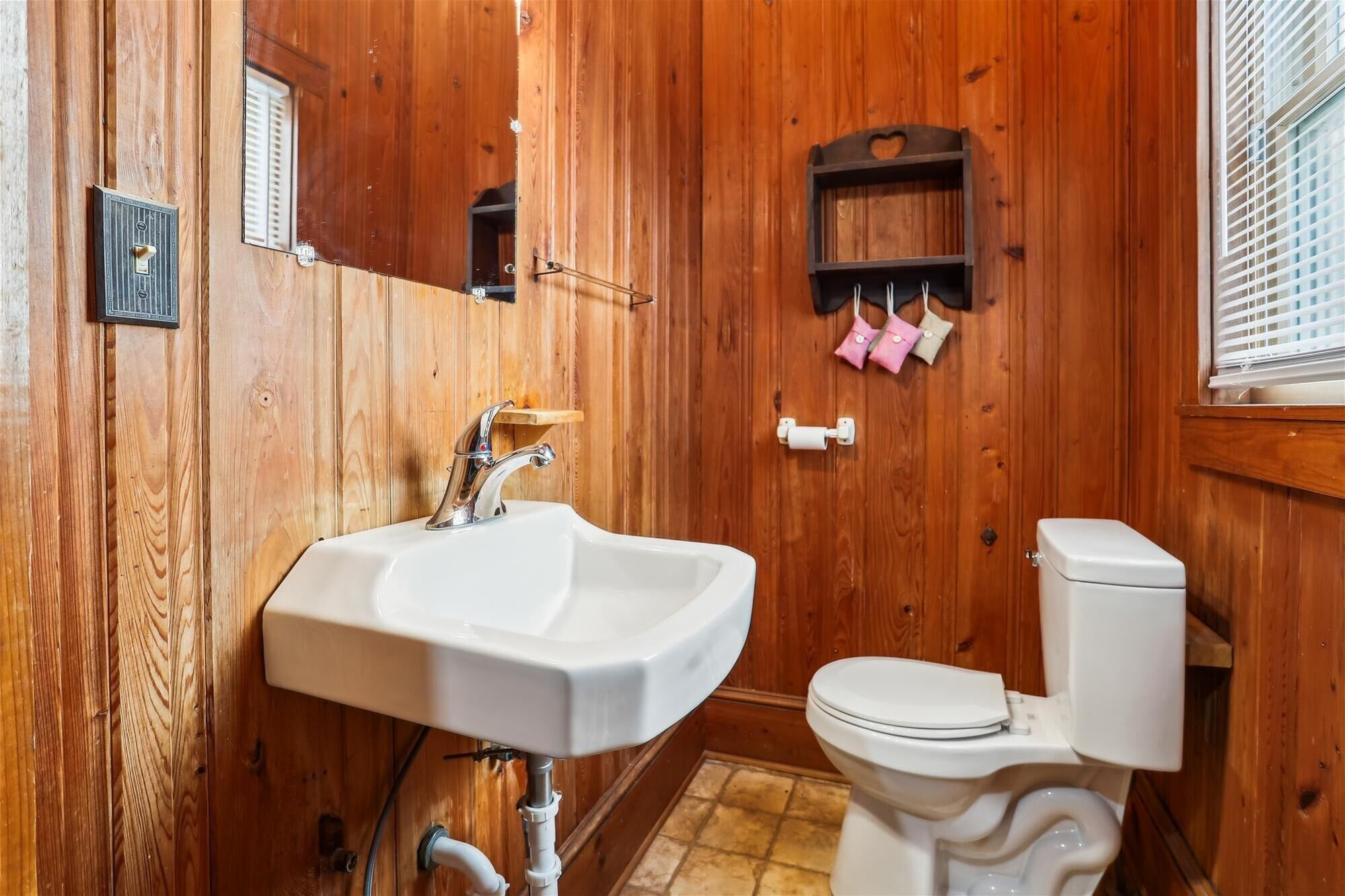 Un bagno con arredamento in legno, un lavandino bianco, un water e uno specchio.