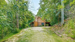Een chalet omringd door dicht bos, bereikbaar via een grindpad.