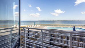 A pool area with a view of the sea, wooden deck, and lounge chairs. - Bayfront Retreat with Pool, Perfect for 6 - PBC108 (Pensacola Beach)