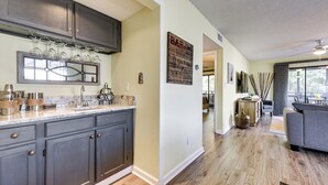 A modern kitchen with dark cabinets, a marble countertop, and a wine rack. - 1 Mi to Coast: Myrtle Beach Condo w/ Balconies! (Myrtle Beach)