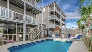 A pool area with a clear blue pool, wooden deck, and multiple levels of balconies.