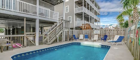 A pool area with a clear blue pool, wooden deck, and multiple levels of balconies.