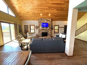 A living room with a stone fireplace, a television, and a large sofa.