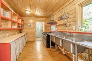 A compact kitchen with wooden walls, a stainless steel sink, and a stove.