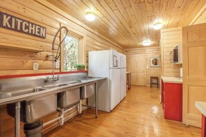 A kitchen with wooden walls, a stainless steel sink, and a white refrigerator.