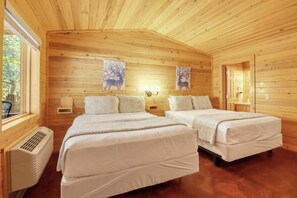 A wooden cabin with two beds, a heater, and artwork on the walls. - Private Resort. Pool, Fire Pit,Sleeps up to 50! Great for reunions/events (Wimberley)
