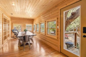 A wooden interior with a dining table, chairs, and large windows. - Private Resort. Pool, Fire Pit,Sleeps up to 50! Great for reunions/events (Wimberley)