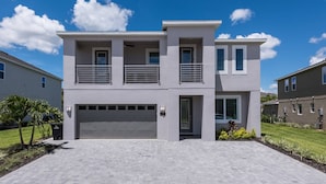Een modern huis met twee verdiepingen, een garage, een balkon en een verzorgd gazon.