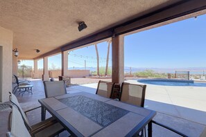 Eine Terrasse im Freien mit Tisch und Stühlen, einem Pool und Blick auf die Berge.