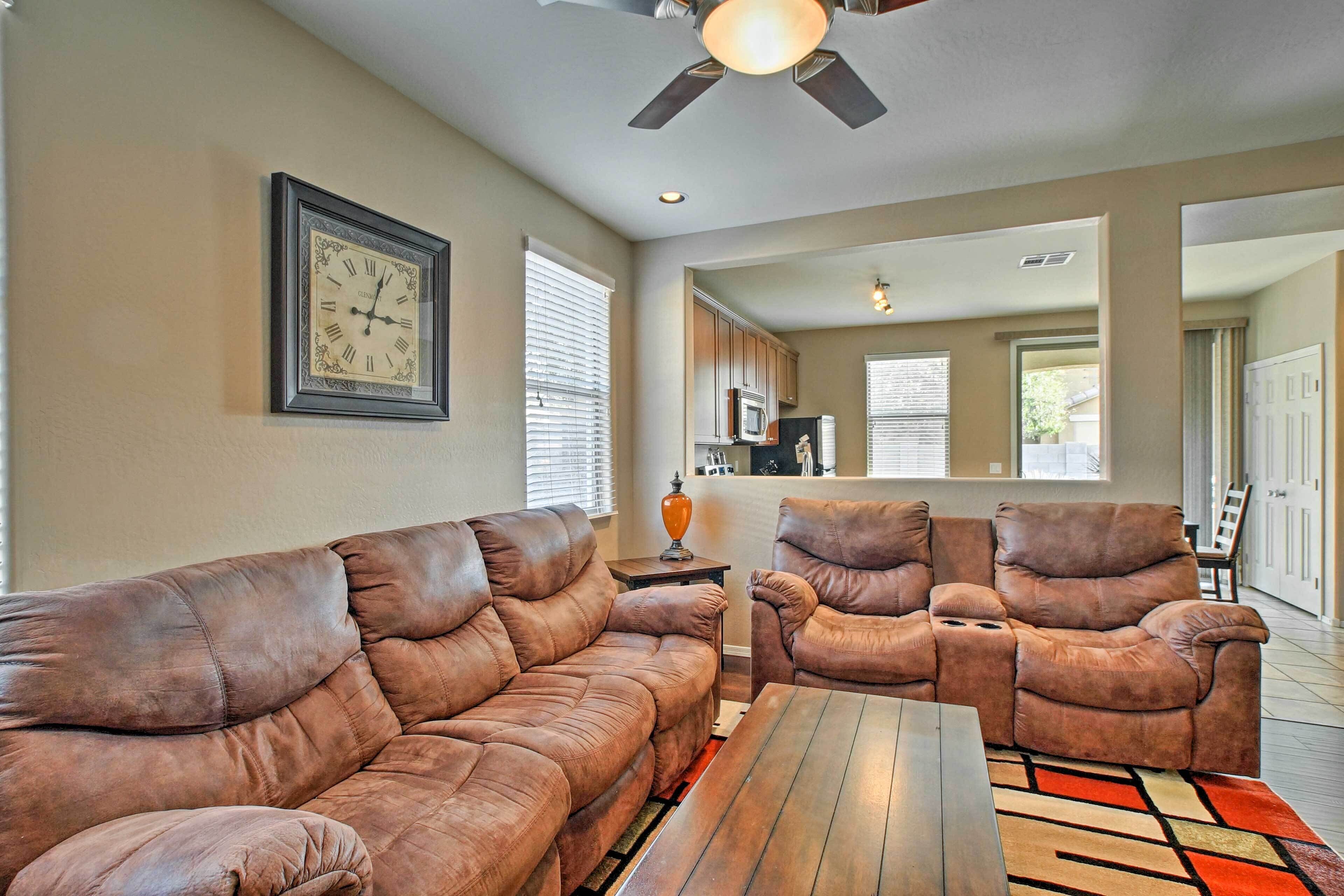 A living room with a brown leather sofa, a wooden coffee table, and a ceiling fan.