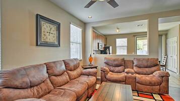A living room with a brown leather sofa, a wooden coffee table, and a ceiling fan.