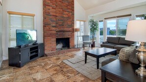 Una sala de estar con chimenea de ladrillo, televisor, sofá y una mesa de centro.