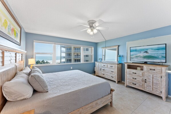 A bedroom with a bed, dresser, TV, and a view of the ocean. - Family & Pet Friendly Condo on the Beach w/ Large Heated Pool 🏖️ (Satellite Beach)