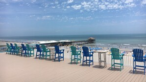 Une terrasse avec des chaises et des tables donnant sur une plage.