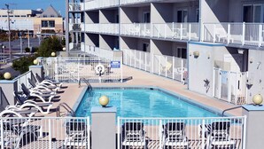 Un área de piscina con varios niveles de balcones, sillas de descanso y una alberca.
