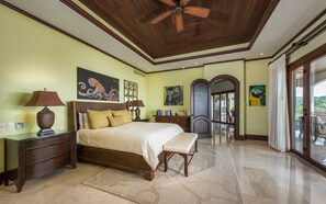 A spacious bedroom with a large bed, a bench, and a ceiling fan.