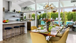 A modern kitchen with a dining area, large windows, and a view of a pool.