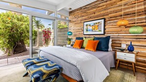 A bedroom with a bed, bedside table, and a view of the outdoors.
