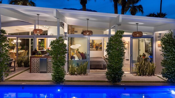 A modern house with a pool, glass doors, and a covered patio area.