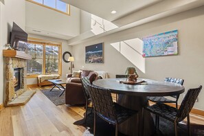 A spacious living area with a fireplace, a round dining table, and modern furniture.